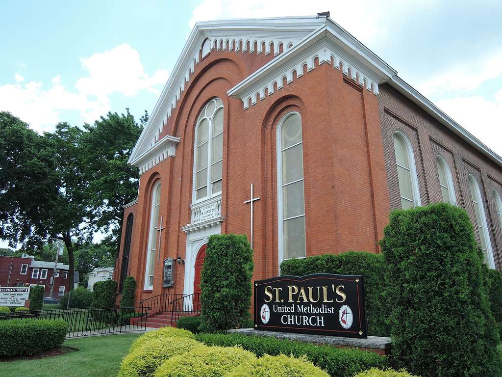 A view of the front of St. Paul's, a red brick church with white trim and tall stained glass windows